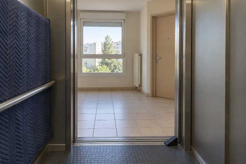 Palier d'étage vu depuis l'intérieur d'une cabine d'ascenseur maintenue ouverte par une cale