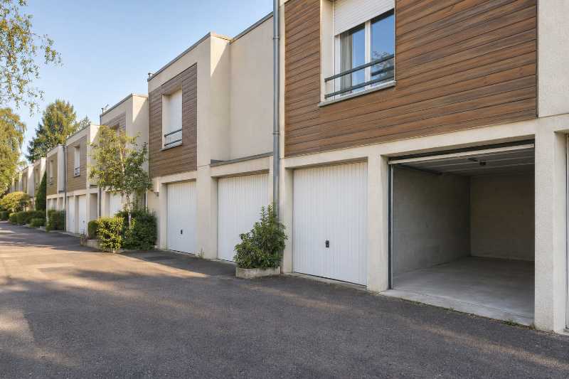 Rangée de maisons de ville dont un seul garage intégré est ouvert et vide